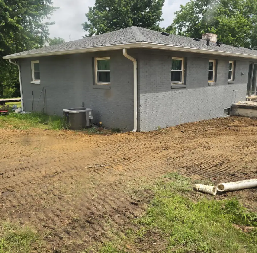 Fresh grading around a gray brick house