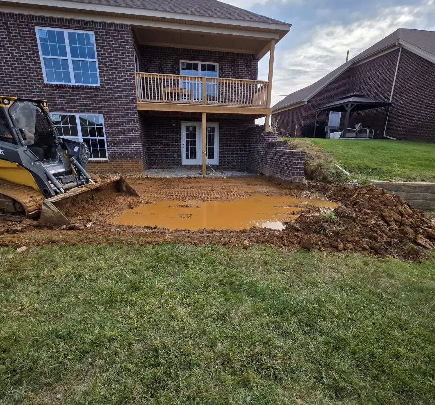 Skid steer regrading a backyard behind a brick home